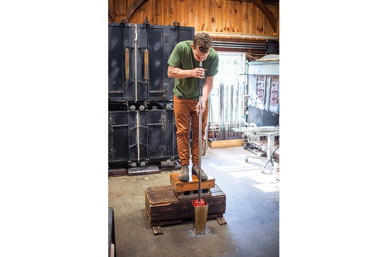 Sideman blows air to inflate a glass form inside a mold.