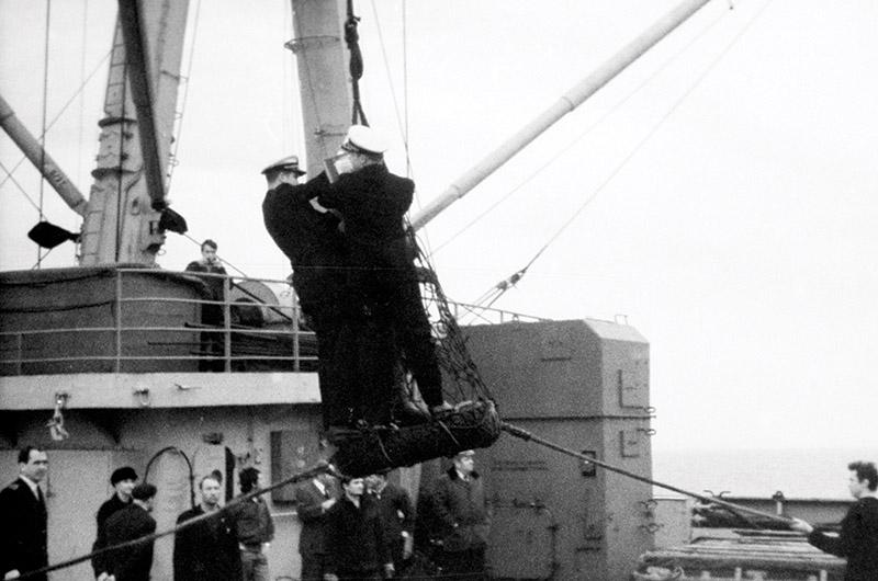 Coast Guard officers from the Vigilant are carried to the fisheries conference aboard the Sovetskaya Litva on a tire suspended from the cargo boom.