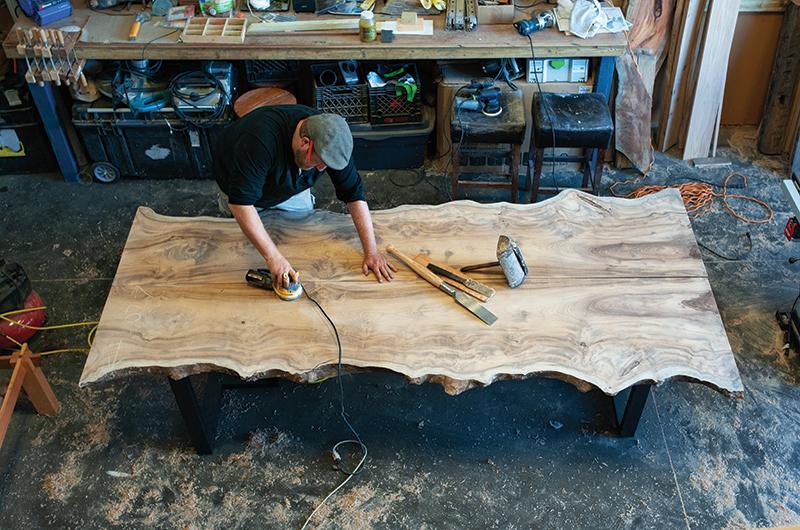 Tucker preps a twelve-foot-long book matched, live edge pair of myrtle slabs, which he will then join together to create one large table.