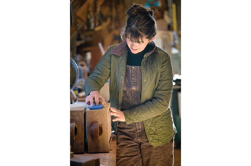 Abbie preps a set of teak drawers for varnish in the Gannon & Benjamin shop.