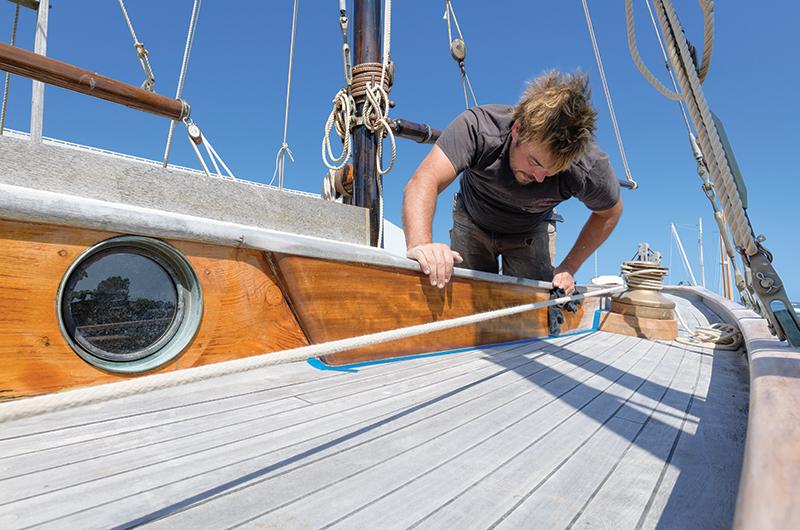 Lyle tapes and tacks down the new iroko cockpit combing before applying varnish.