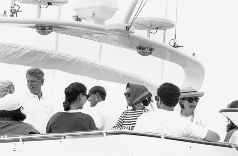 Jacqueline Kennedy Onassis (in striped shirt) with, facing from left, Senator Ted Kennedy, President Bill Clinton, and Hillary C